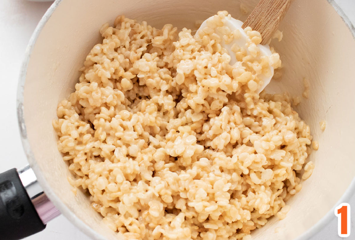 White pan filled with Rice Krispie Treat mixture and a wooden spoon.