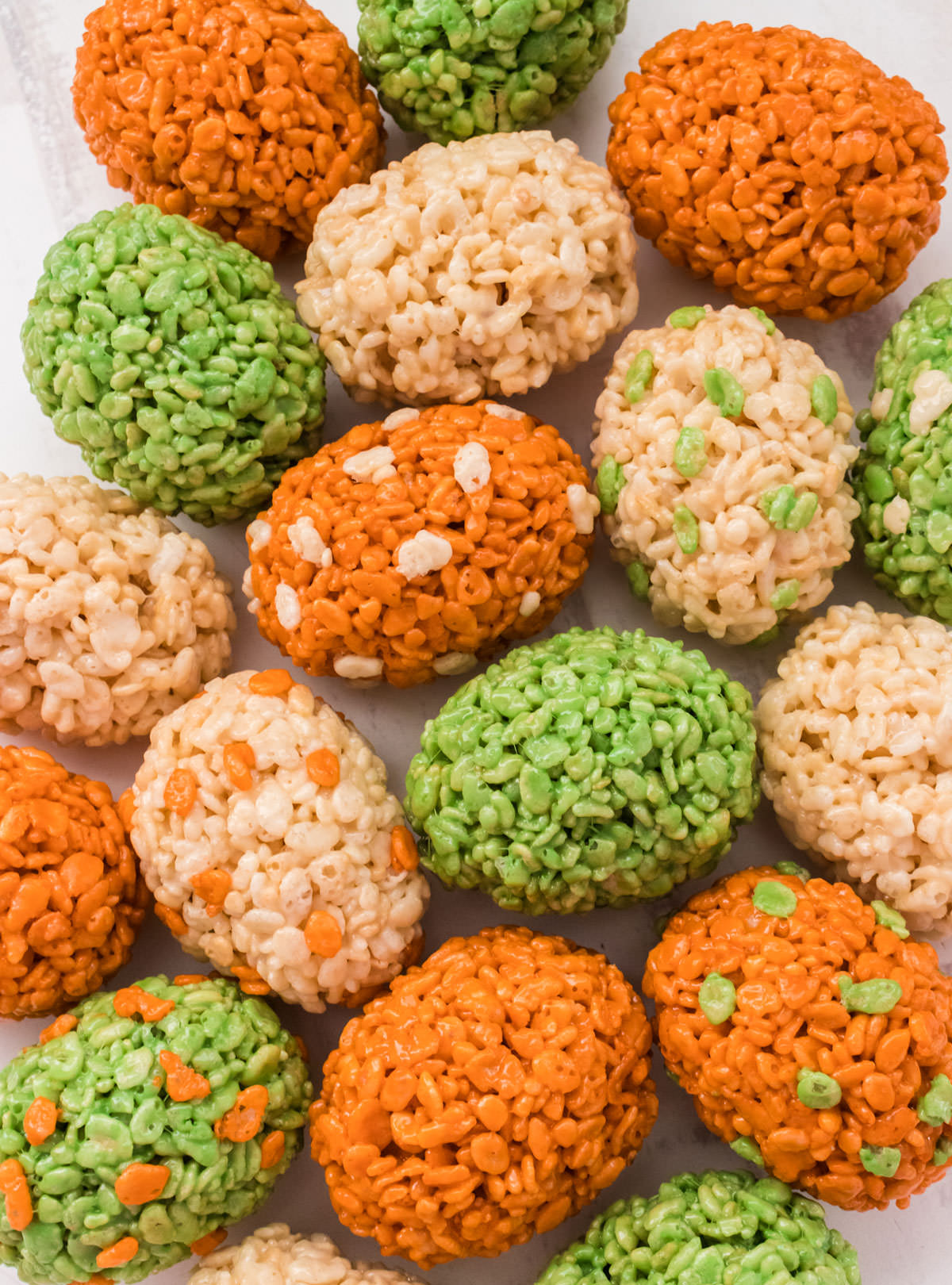 Closeup of 18 Dinosaur Eggs Rice Krispie Treats laying on a white surface.