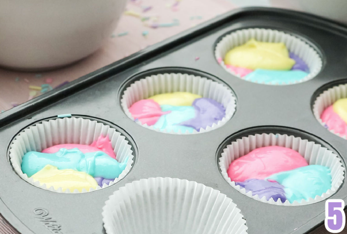 Closeup on a cupcake pan filled with the multi-colored cupcake batter that will create the marble effect in the cupcakes.