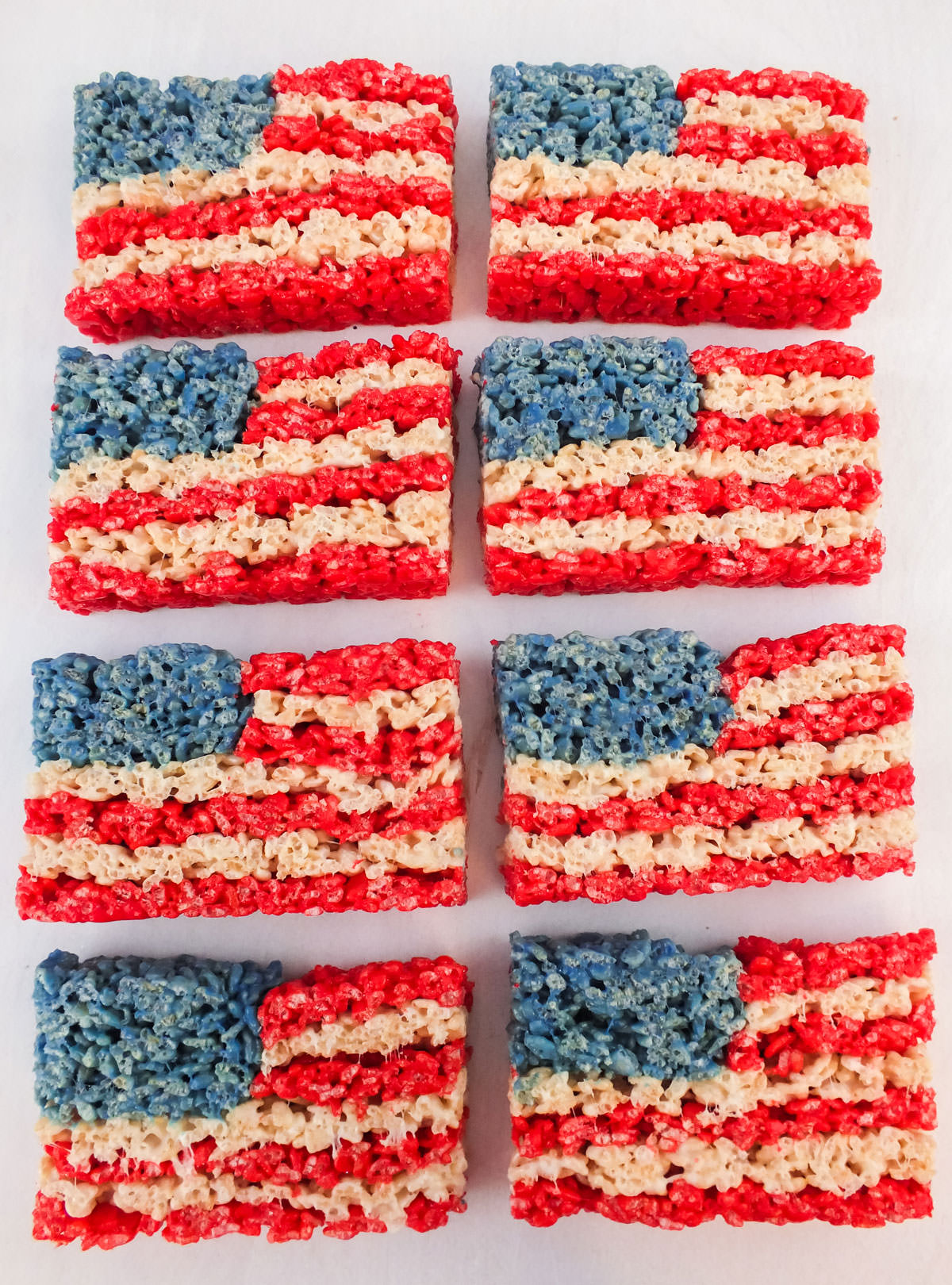 Eight American Flag Rice Krispie Treats laying in rows on a white surface.