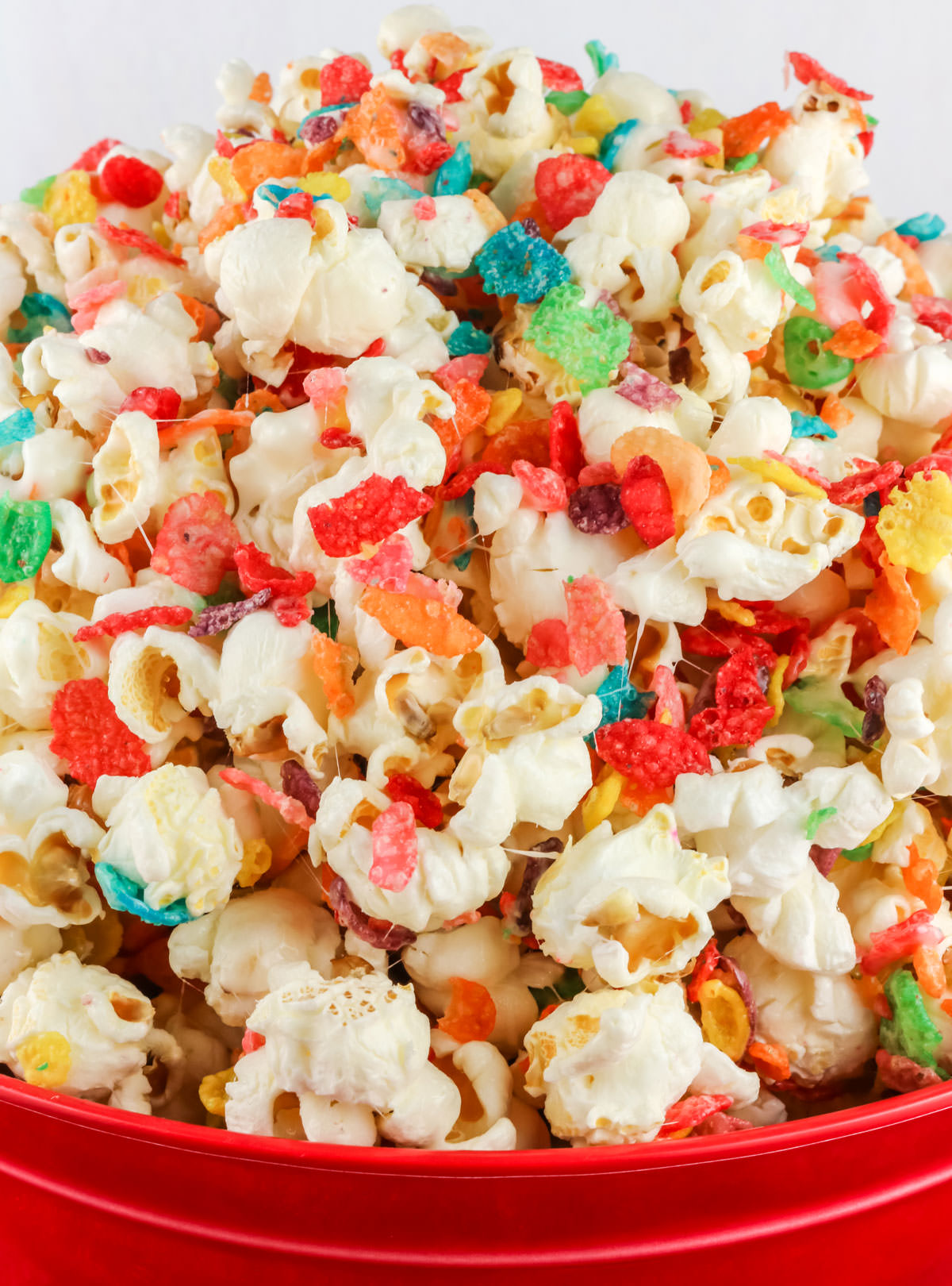 Red serving bowl filled with Fruity Pebbles Popcorn.