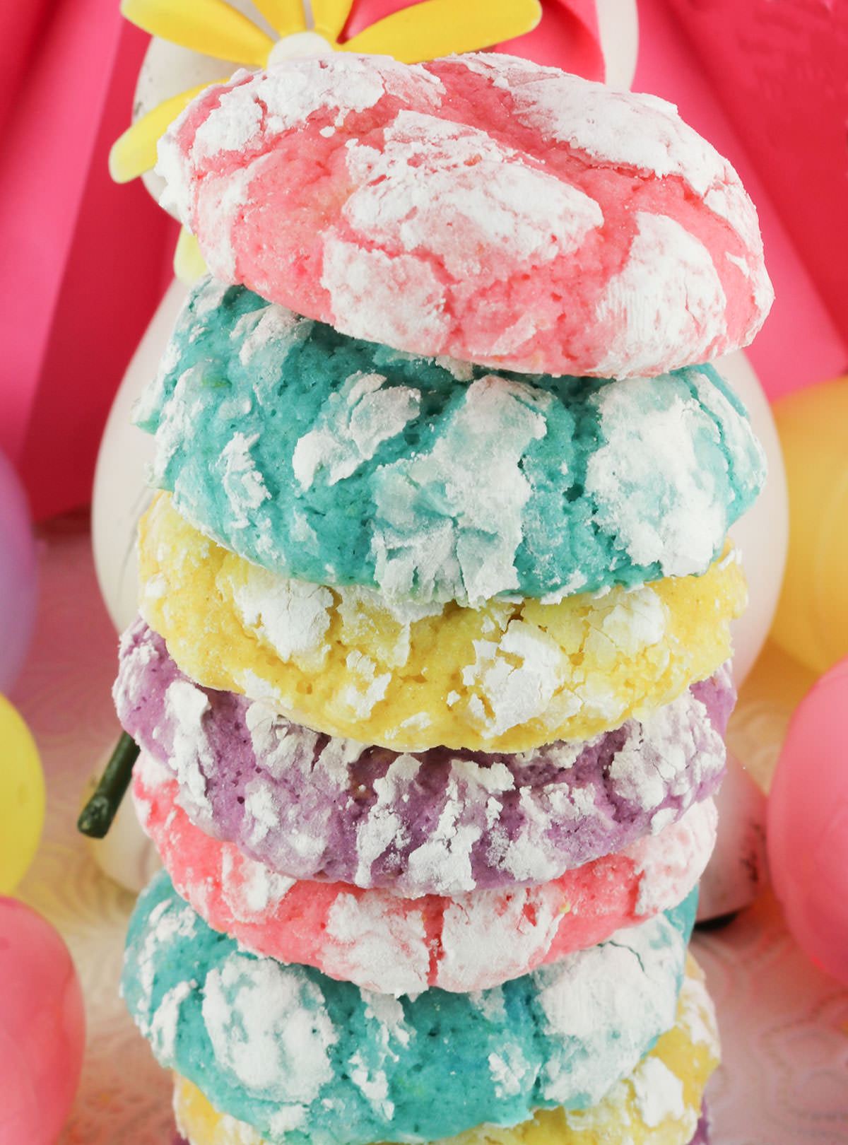 Closeup of a tall stack of Lemon Crinkle Cookies colored in pink, blue, yellow and purple.