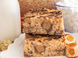 A stack of two Peanut Butter Cup Rice Krispie Treats sitting on a white dessert plate next to a bottle of milk.