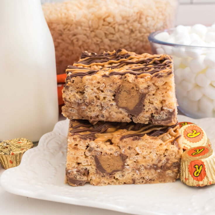 A stack of two Peanut Butter Cup Rice Krispie Treats sitting on a white dessert plate next to a bottle of milk.