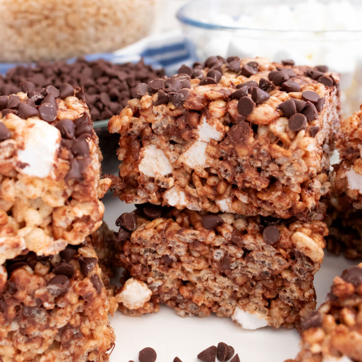 A batch of Zebra Rice Krispie Treats sitting on a white table surrounded by clear bowls full of cereal and marshmallows.