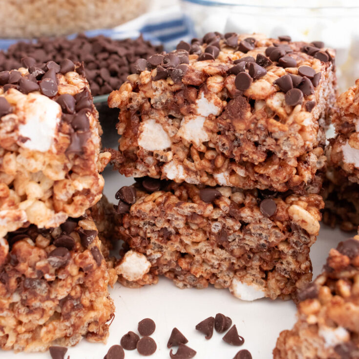 A batch of Zebra Rice Krispie Treats sitting on a white table surrounded by clear bowls full of cereal and marshmallows.