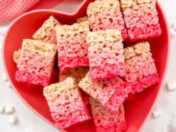 A batch of Ombre Rice Krispie Treats in a heart shaped bowl laying on a white table.